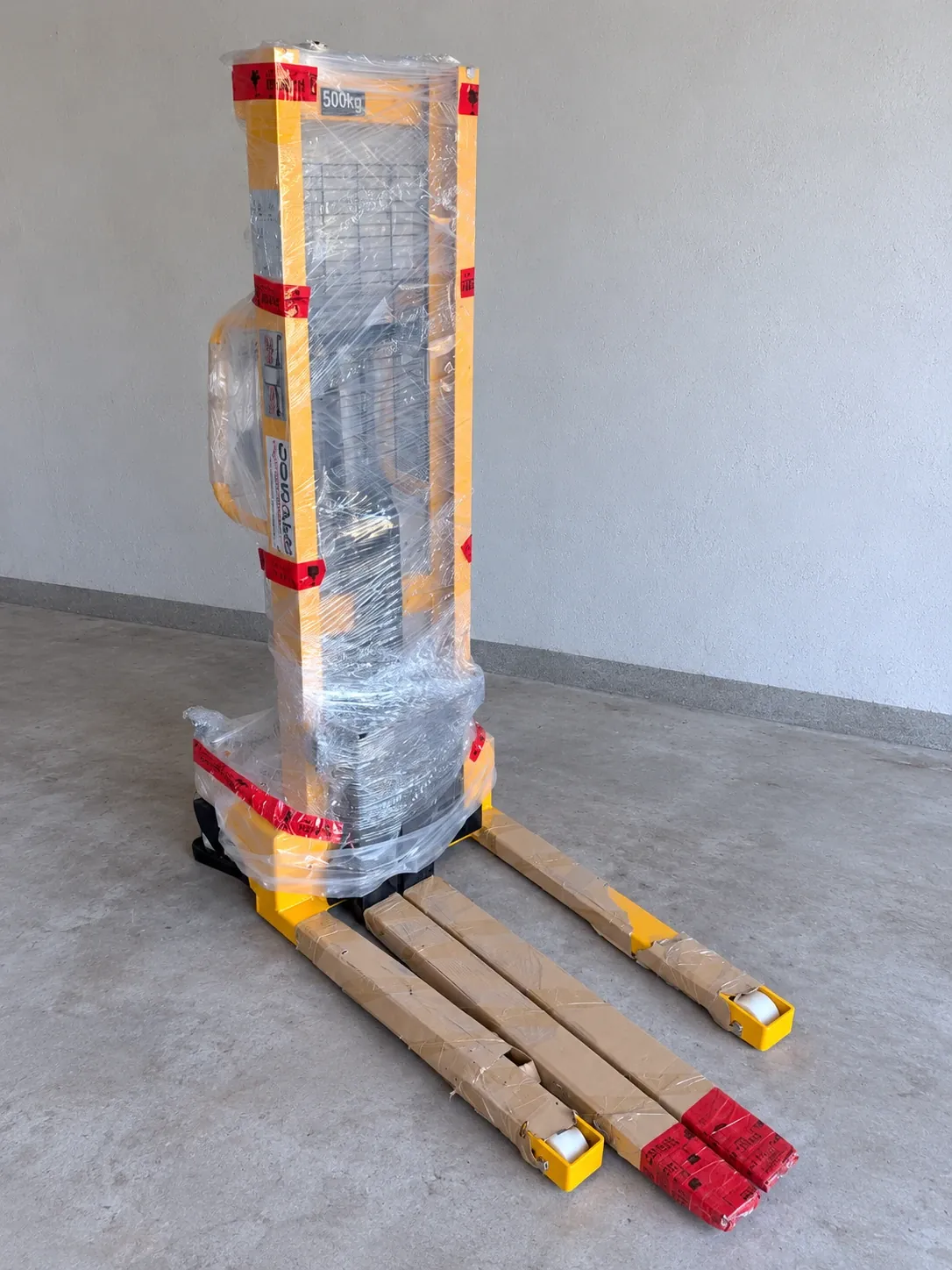 Neuer gelber Hochhubwagen mit 500 kg Tragfähigkeit, frisch angeliefert und noch in Transportfolie verpackt